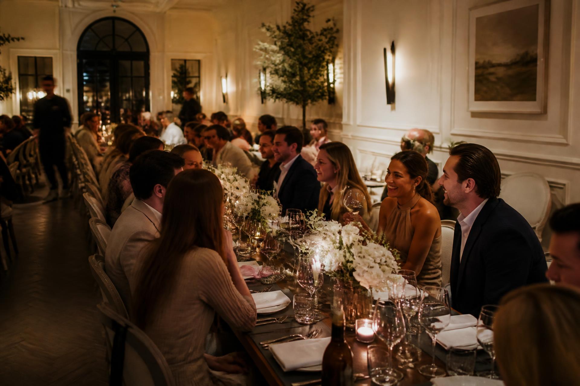 Guests seated at long candlelit tables in an intimate contemporary events room